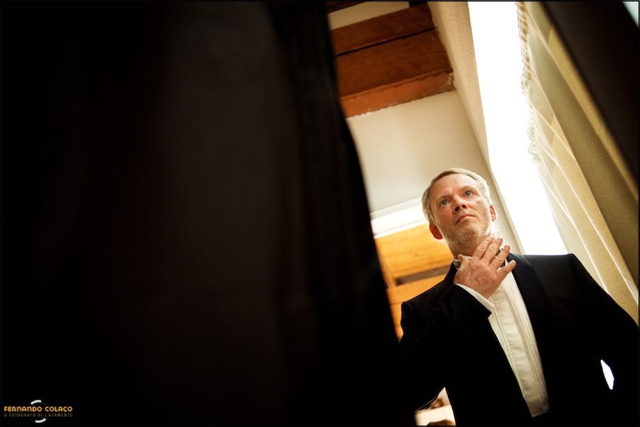 Once ready for the wedding ceremony, the groom checks the bow on his neck.