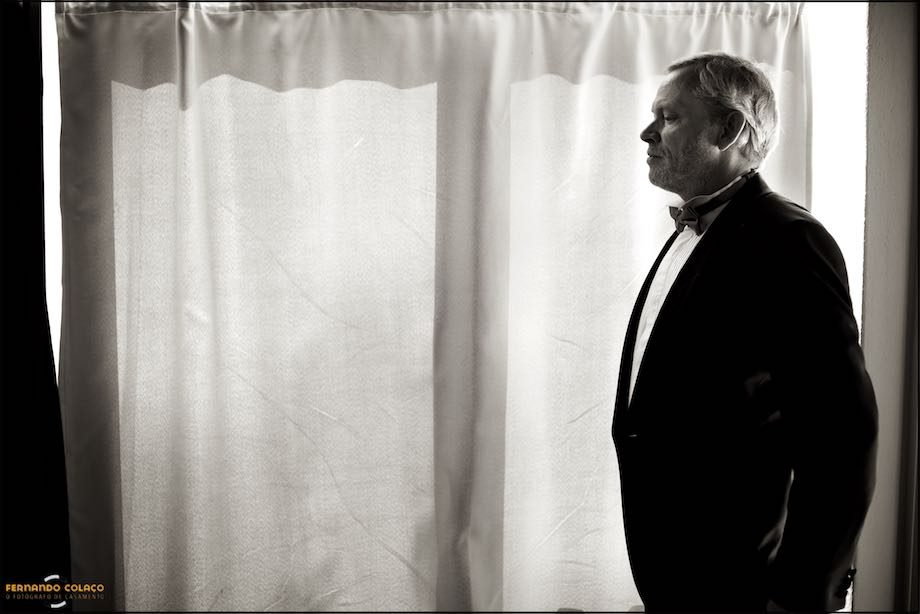 A quiet moment of the groom, in profile, in front of a window, before leaving for the wedding ceremony.