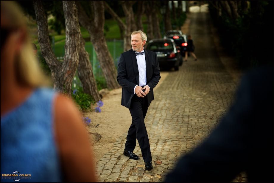 The groom on the way to Morada do Sol in Sintra, seen between two unfocused guests for the wedding ceremony.