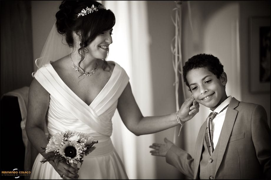 The bride, bouquet in hand, playfully tugs a boy's ear before leaving for the wedding ceremony.
