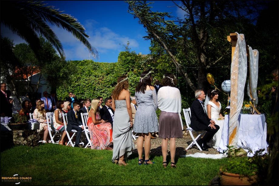 Guests seated at the wedding ceremony site, with the bride and groom in front, at the wedding ceremony table at Morada do Sol.
