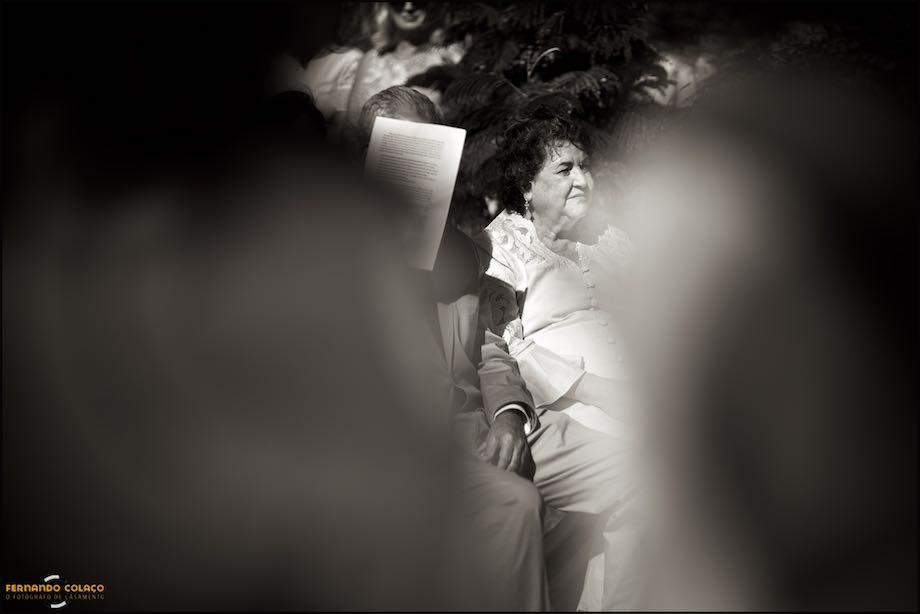 Among the blurred bride and groom, a lady watches the wedding ceremony.