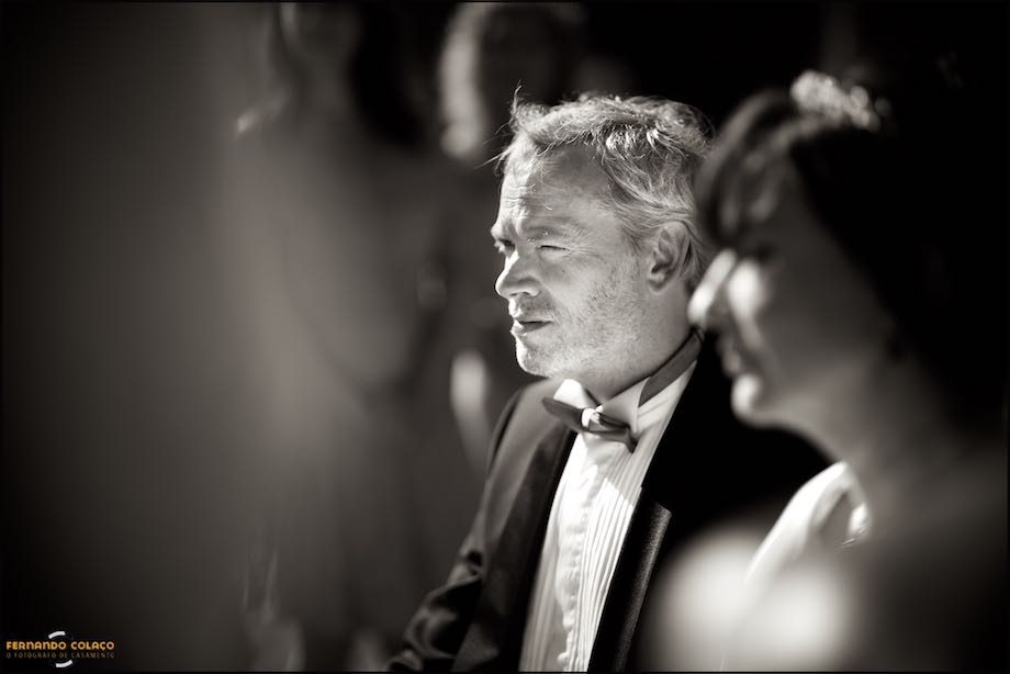 The groom, beside the bride, out of focus, listening intently to the officiant of the wedding ceremony.
