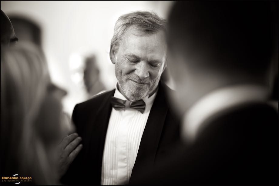 The groom, emotional, among guests, out of focus, when they greet him on the wedding.