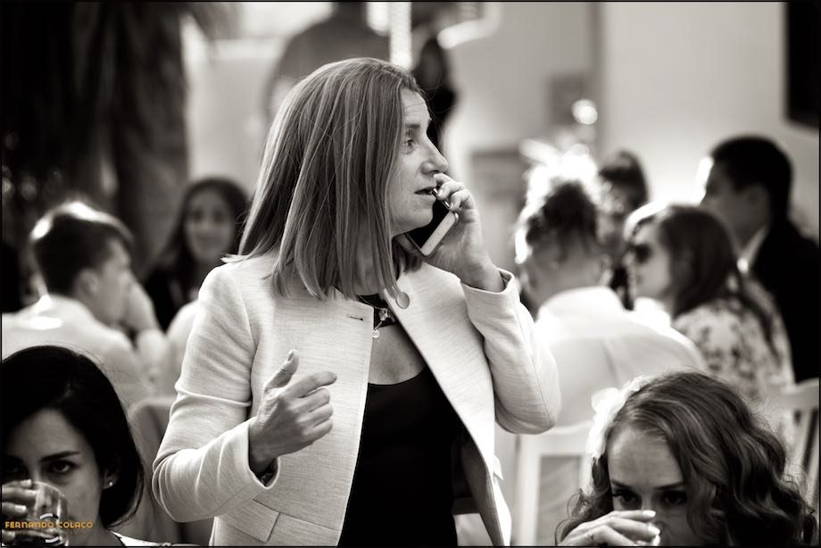 A wedding guest on the phone, in front of others seated at the table.
