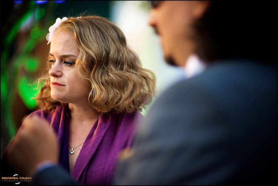 A female wedding guest, in profile, listening to someone.
