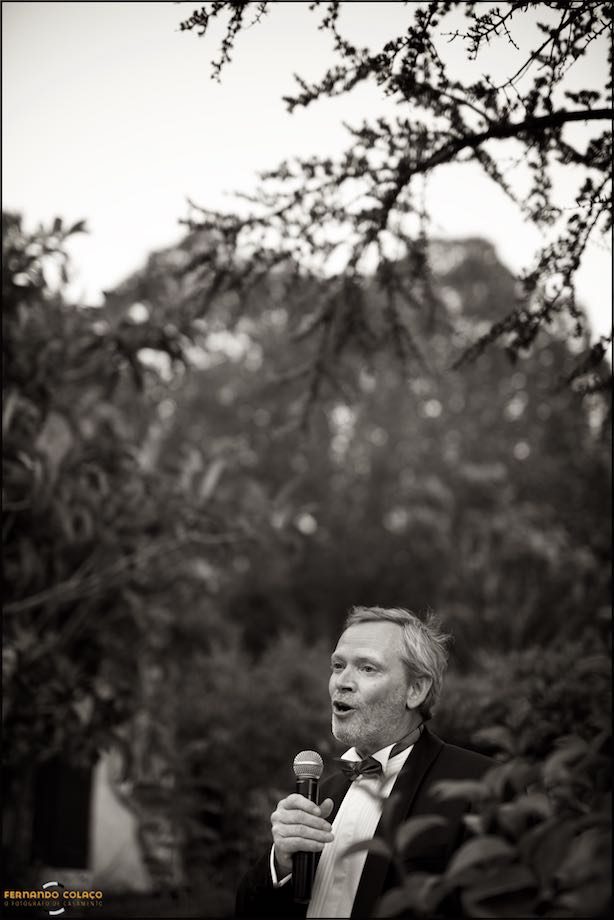 The groom, with the trees in the garden of Morada do Sol in Sintra behind, speaks to his wedding guests.