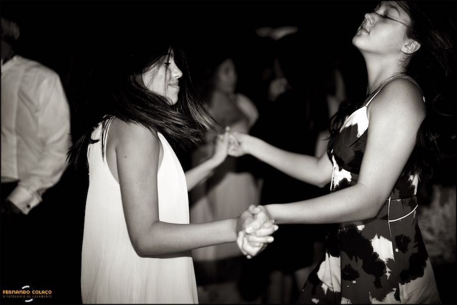 Two young girls wedding guests dance hand in hand facing each other.