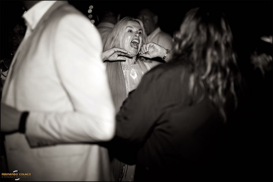 A wedding guest laughs a lot as she dances among the other wedding guests.