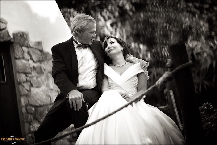 The groom hugs the bride sitting on a chair in the garden of Morada do Sol in Sintra.