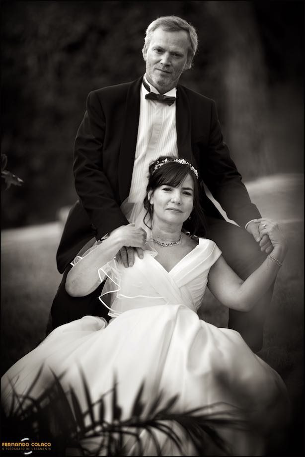 The groom supports the bride, leaning against his chest, who holds her hands, in a pose for the wedding photographer.