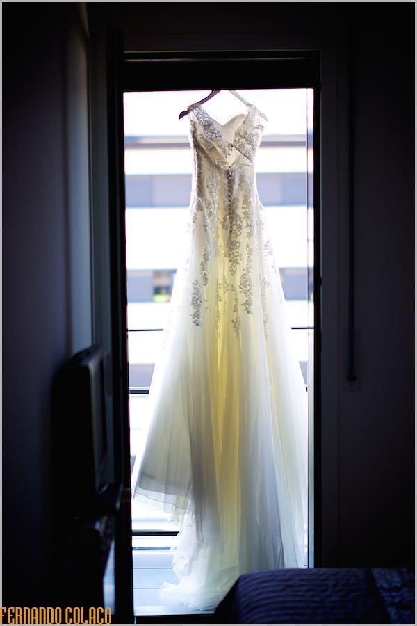 O vestido da noiva pendura na janela que dá para a varanda.