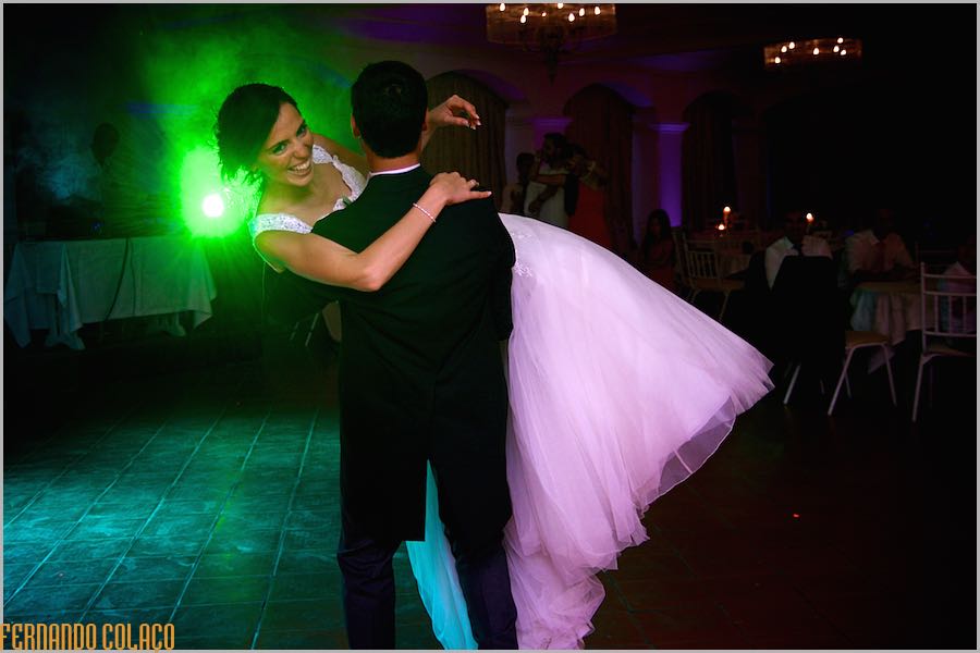 No fim da primeira dança, o noivo com a noiva ao colo, iluminados por uma luz verde por detrás deles.