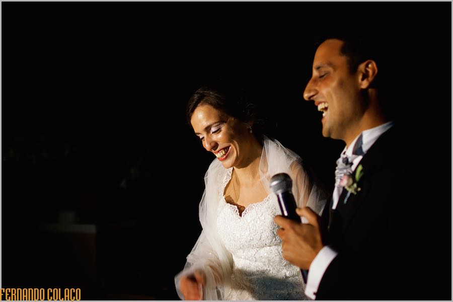 Antes do corte do bolo do casamento, os noivos discursam, rindo muito, agradecendo aos seus convidados.
