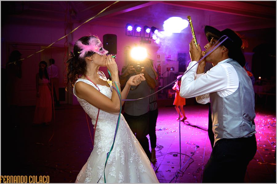 Os noivos, de frente um para o outro, com máscaras brincam um com o outro durante a festa do casamento na Casa de Reguengos.