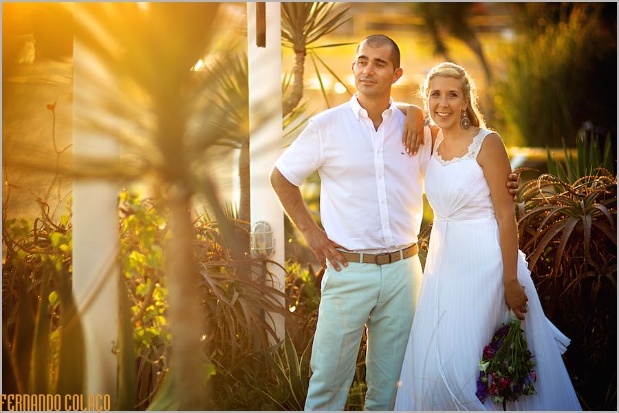 The couple, just married, enveloped in a late afternoon orange light in Praia Grande, by the wedding photographer.