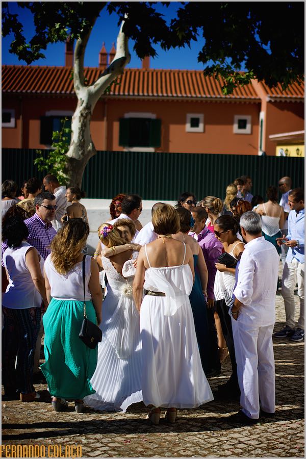 In front of the church where the wedding took place, the bride hugs a guest, surrounded by many others.