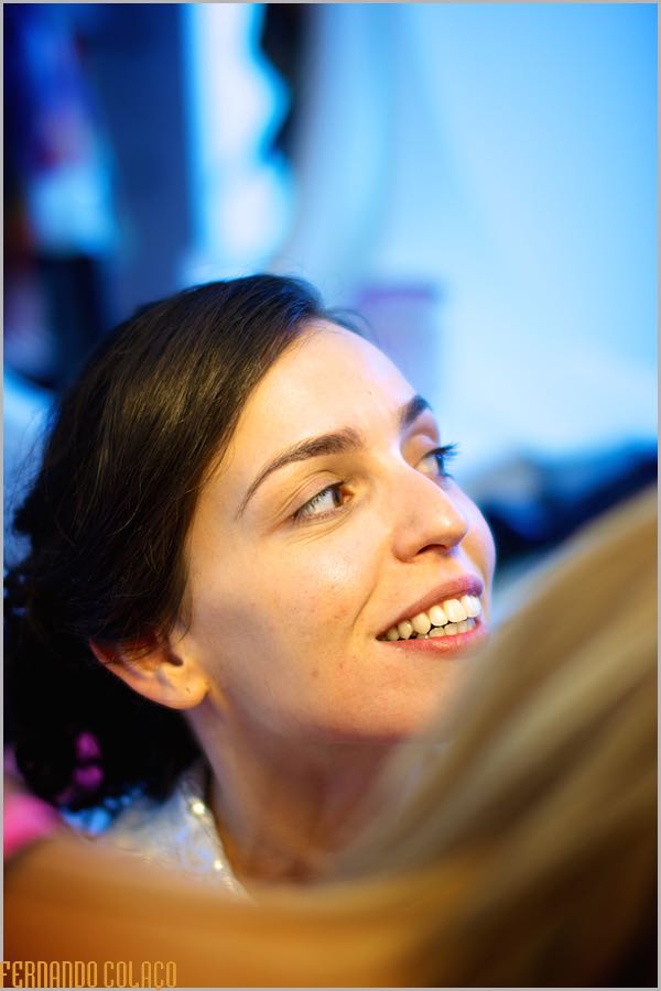 Bride's face smiling as she talks to someone, at the stage when she is getting her hair done for the wedding.