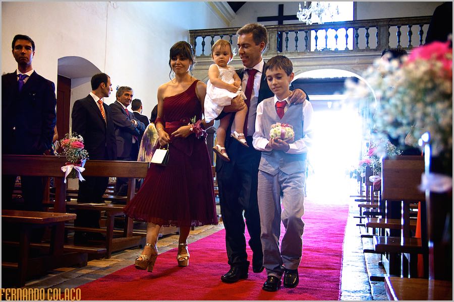 A couple of wedding guests walk with their children to their place inside the Church of Nossa Sra. da Assunção of Enxara do Bispo.
