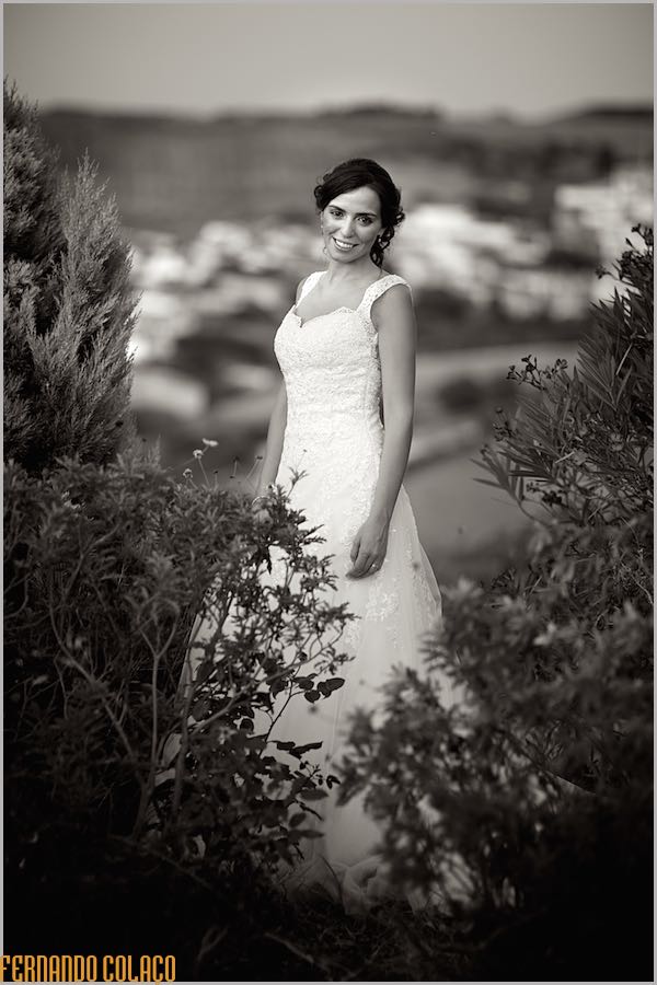 Portrait of the bride in black and white, looking straight ahead and framed by two tufts of plants, taken by the wedding photographer.
