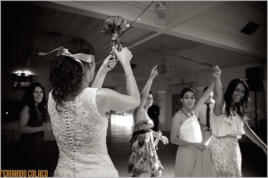 The bride with the bouquet in her hands, aloft, before tossing it to the singles at the wedding, in front of her.
