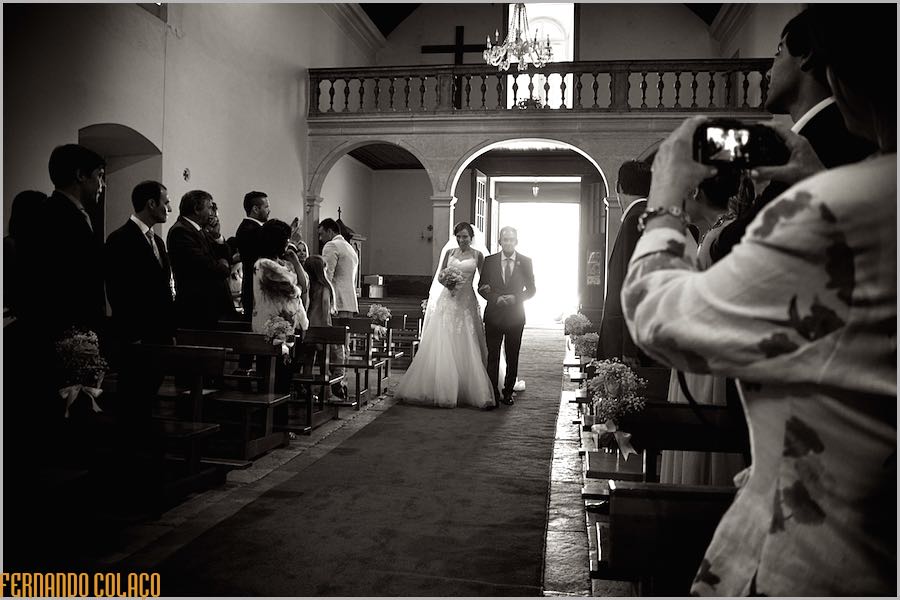 The bride enters the Church of Nossa Sra. of the Assumption of Enxara do Bispo, with her father, among the guests towards the altar.