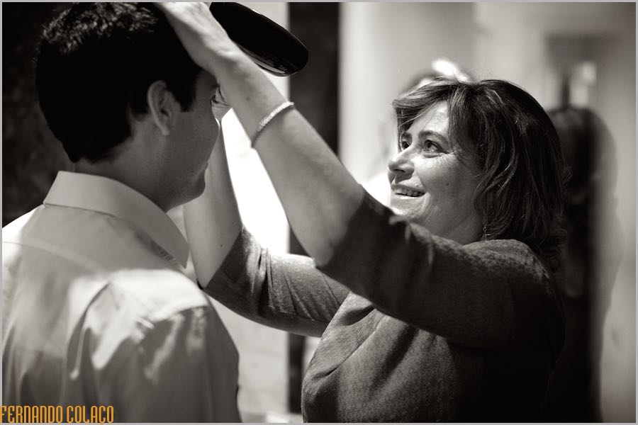 The groom with his mother who fixes his hair, smiling.