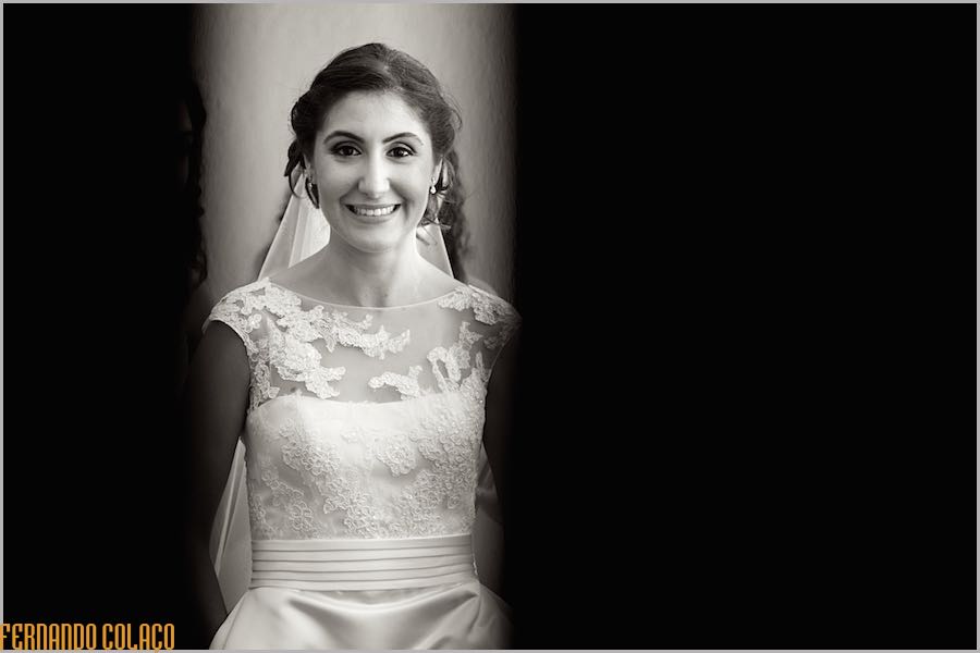 Bride smiling, in the middle of two dark zones, in a portrait by the wedding photographer.