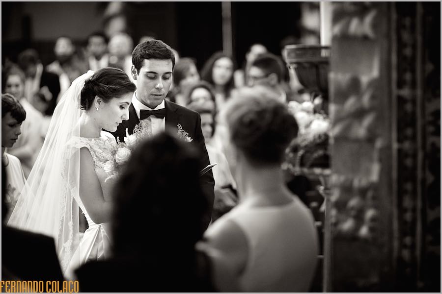 In the midst of the guests, the bride and groom offer flowers to the patron saint of the church, at the end of the wedding ceremony, viewed by the wedding photographer in Lisbon.