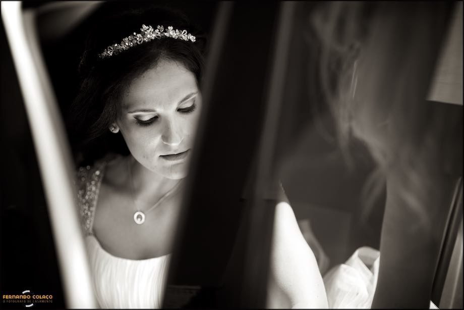 The bride adjusts the dress inside the car.