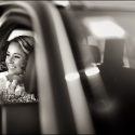 Big smile from the bride as she arrives at the church for the wedding ceremony in the car, viewed by the wedding photographer.