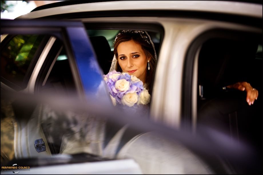 Bride getting out of the car with the bouquet close to her face.