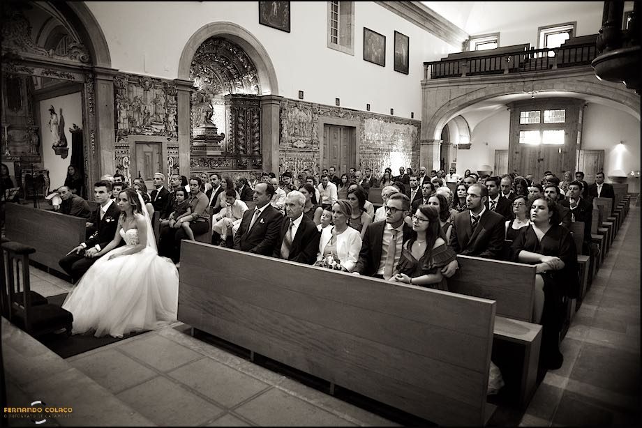 A Igreja Paroquial de Nossa Senhora da Assunção em Cascais, com os noivos à frente de todos os convidados do casamento, sentados, a seguir o desenrolar da cerimónia.