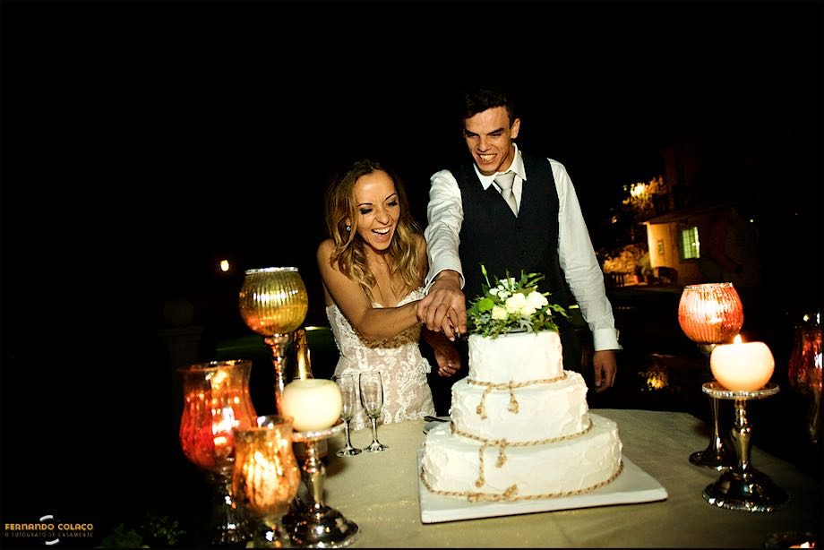 Os noivos rindo de alegria quando cortam o bolo do casamento na Quinta das Palmeiras em Sintra.