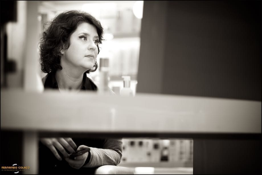 A noiva depois de maquilhada para o casamento, vista entre prateleiras no cabeleireiro.