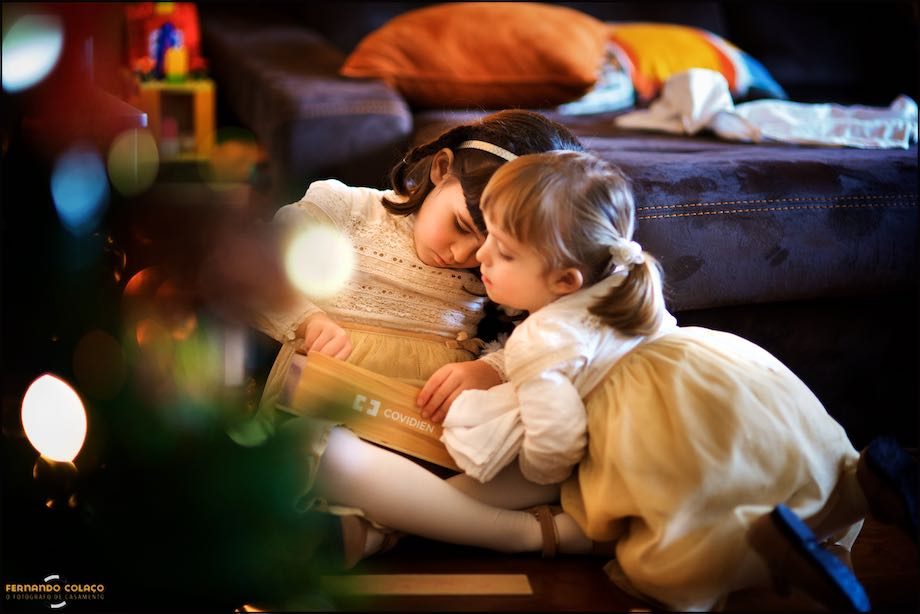 Depois de vestidas para o casamento dos pais, as duas irmãs brincam junto da árvore de Natal.