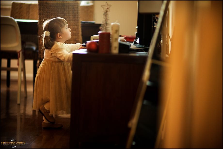 A filha mais nova dos noivos junto de um móvel a ver televisão.