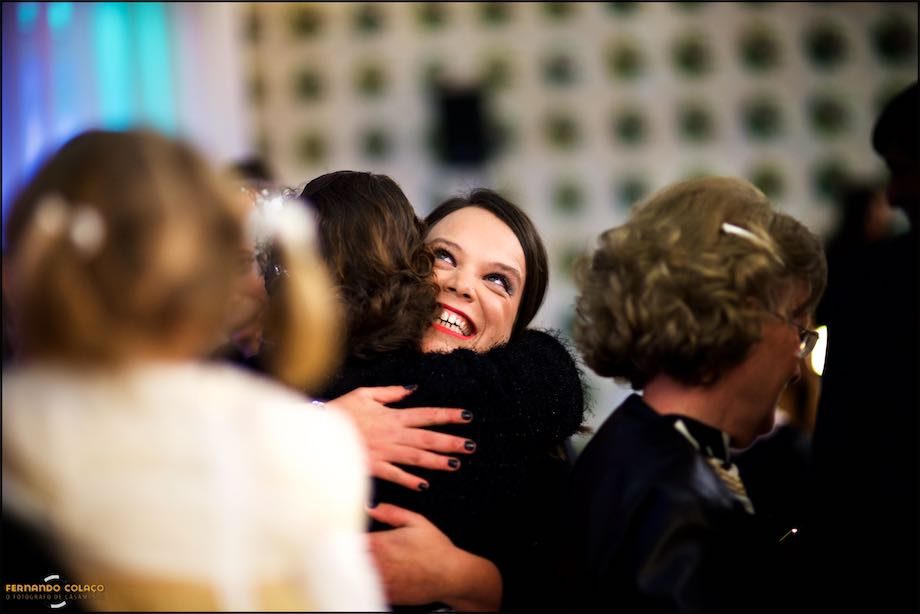 Uma convidada do casamento, rindo de felicidade, abraça a noiva antes da cerimónia do casamento.