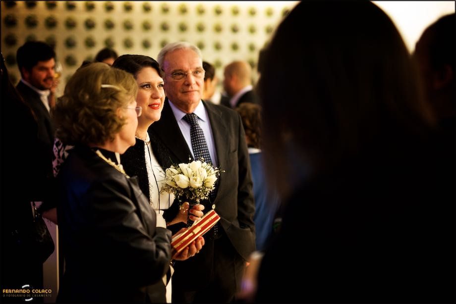 A noiva junto de um casal de convidados do casamento num convívio, enquanto espera pela cerimónia do casamento.