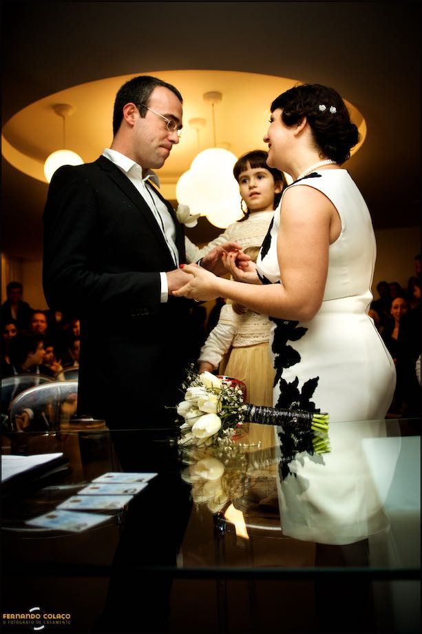 Os noivos olhando um para o outro, depois da cerimónia das alianças do casamento com a filha mais velha entre eles.