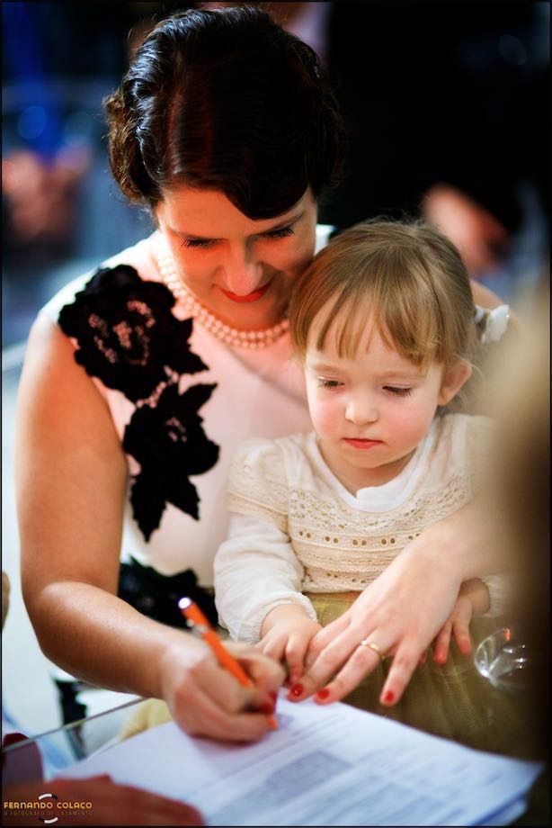 Noiva com a filha mais nova no colo, enquanto assina os documentos do casamento.