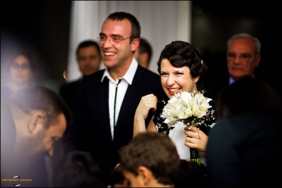 Os noivos riem contentes entre os convidados, quando acabou a cerimónia do casamento.