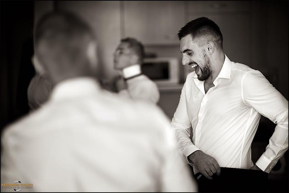 The groom laughing among his friends as he dresses for the wedding.