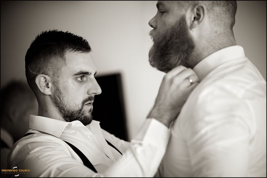 The groom tightens the shirt collar of one of his friends, a guest at the wedding.