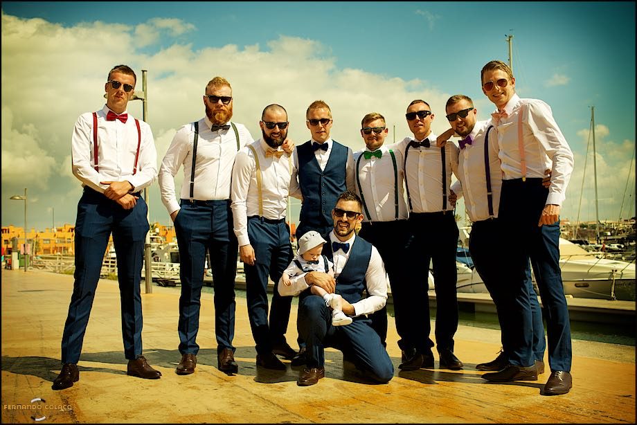 As if it were a football team for the picture before the game, the groom, with his baby son in his arms, with his friends ready for the wedding day.
