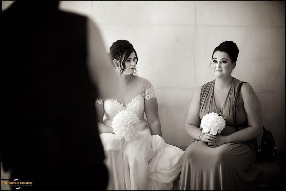 The bride sitting next to her sister as she waits for the wedding ceremony to take place at Club Nau in Ferragudo.