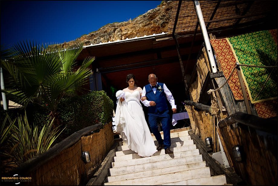 The bride, with her father, descends the steps of the Club Nau that takes her to Praia Grande where the wedding ceremony takes place.