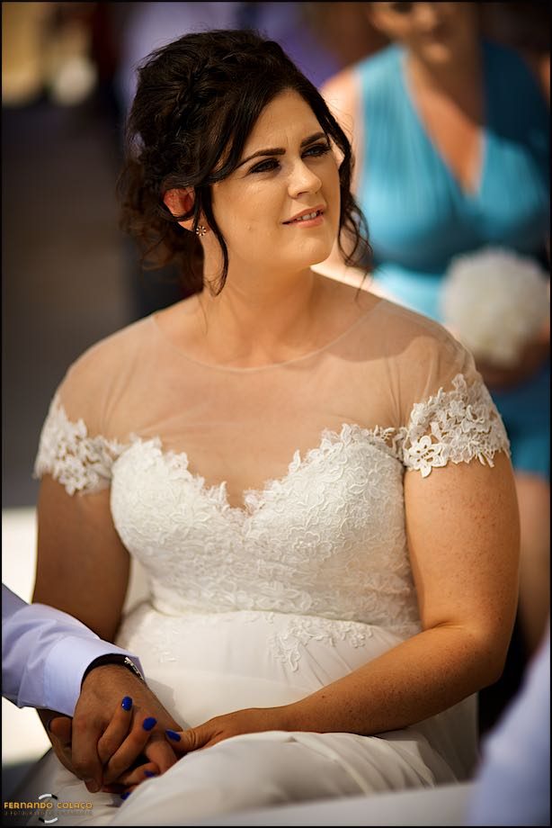 The bride, at the wedding ceremony, looks to the side, where the officiant is.