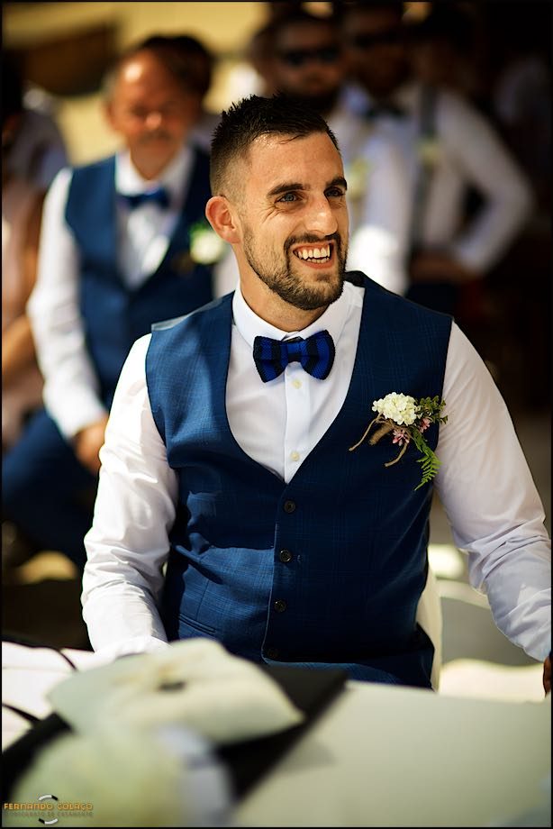 The groom, sitting, laughing with satisfaction, at the wedding ceremony.