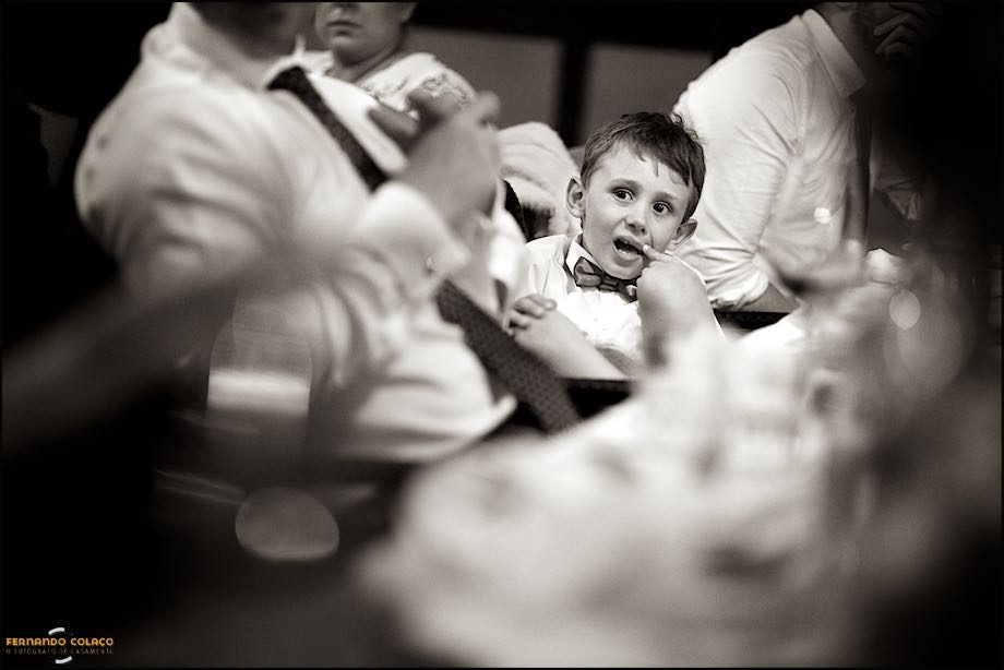 A boy with a finger in his face as the speeches at the wedding take place, seen among other blurred people.